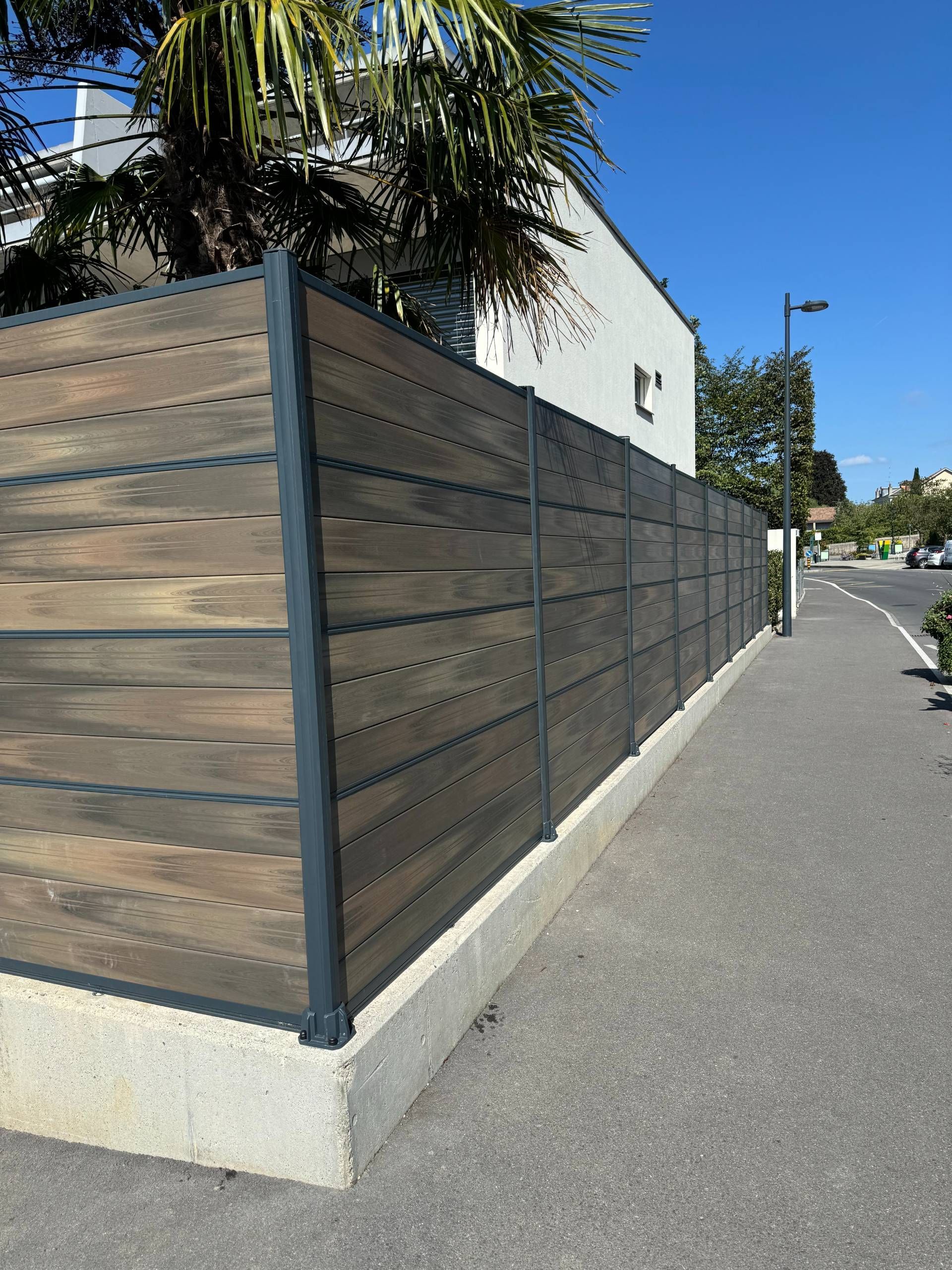 Clôture moderne imitation bois le long d'un trottoir.