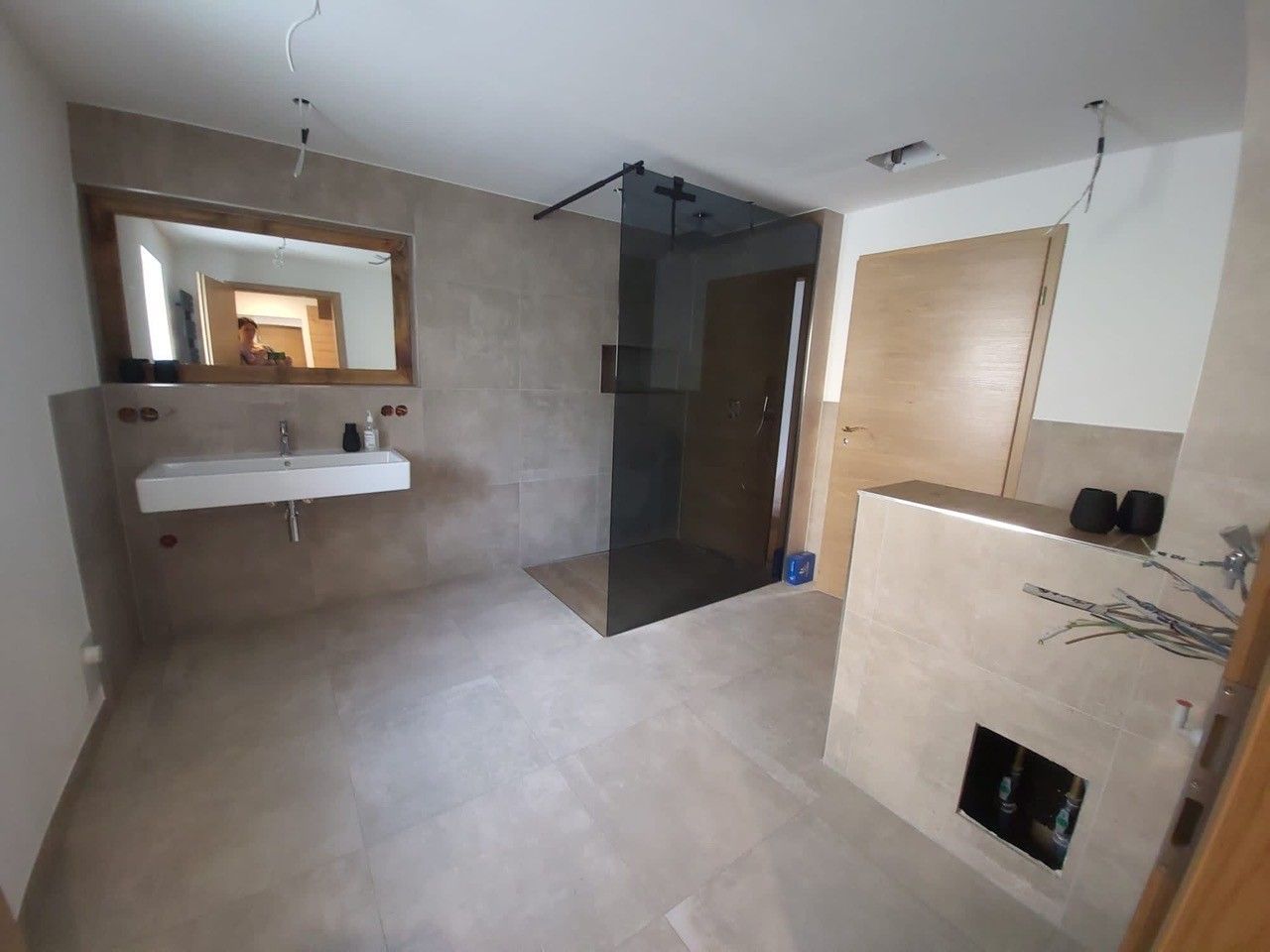 Helles, modernes Badezimmer mit frei stehendem Waschtisch und großer, dunkler Dusche.