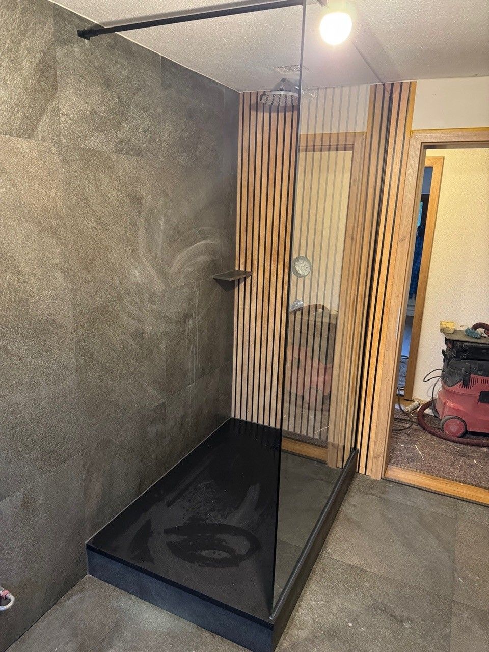 Modernes Badezimmer mit dunkler begehbarer Dusche und Holzverkleidung an der Wand