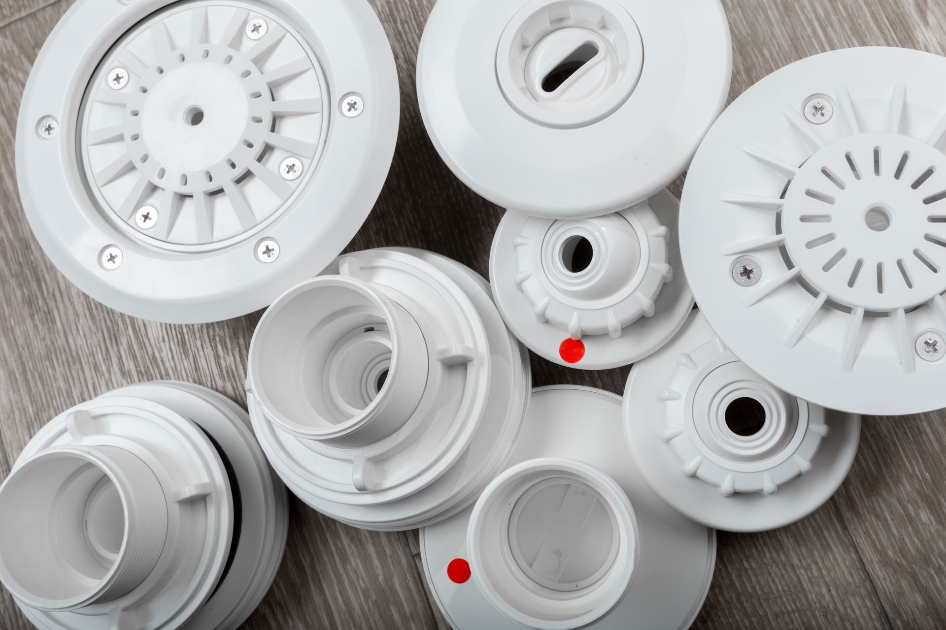 Chorros de agua y accesorios para piscina o spa de color blanco sobre superficie con veta de madera.