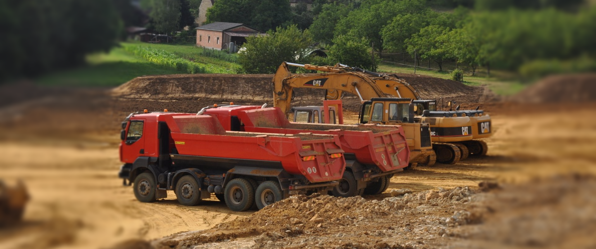 Camion-benne rouge et excavatrice jaune sur un chantier boueux