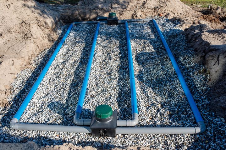 Cadre en tuyau bleu sur du gravier dans une tranchée creusée, avec un capuchon vert à l'avant