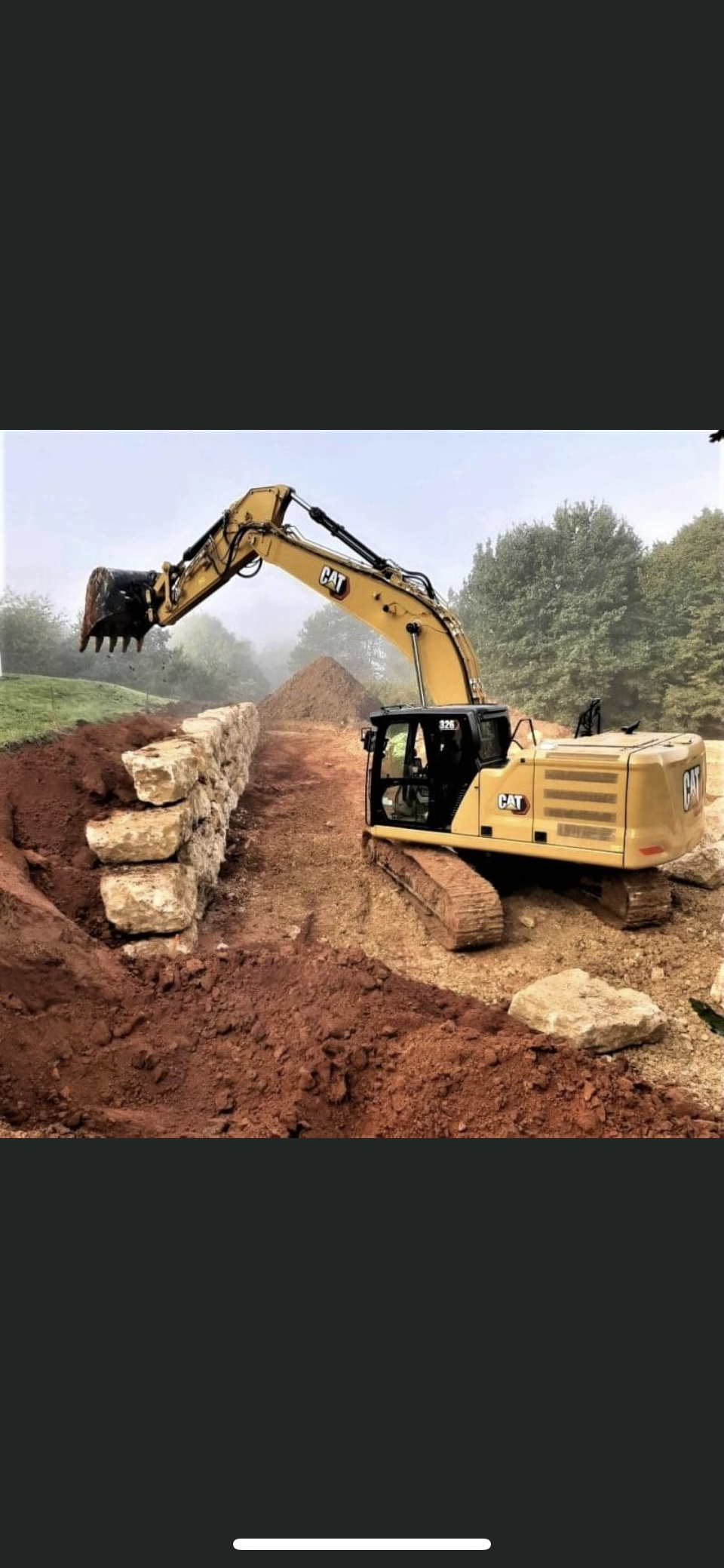 Une pelleteuse jaune creuse un monticule de terre sur un chantier de construction.