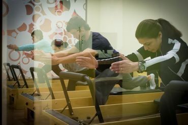 Un grupo de personas está haciendo ejercicios de estiramiento en una máquina de pilates.