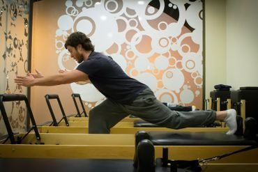 Un hombre se estira en una máquina de pilates en un gimnasio.