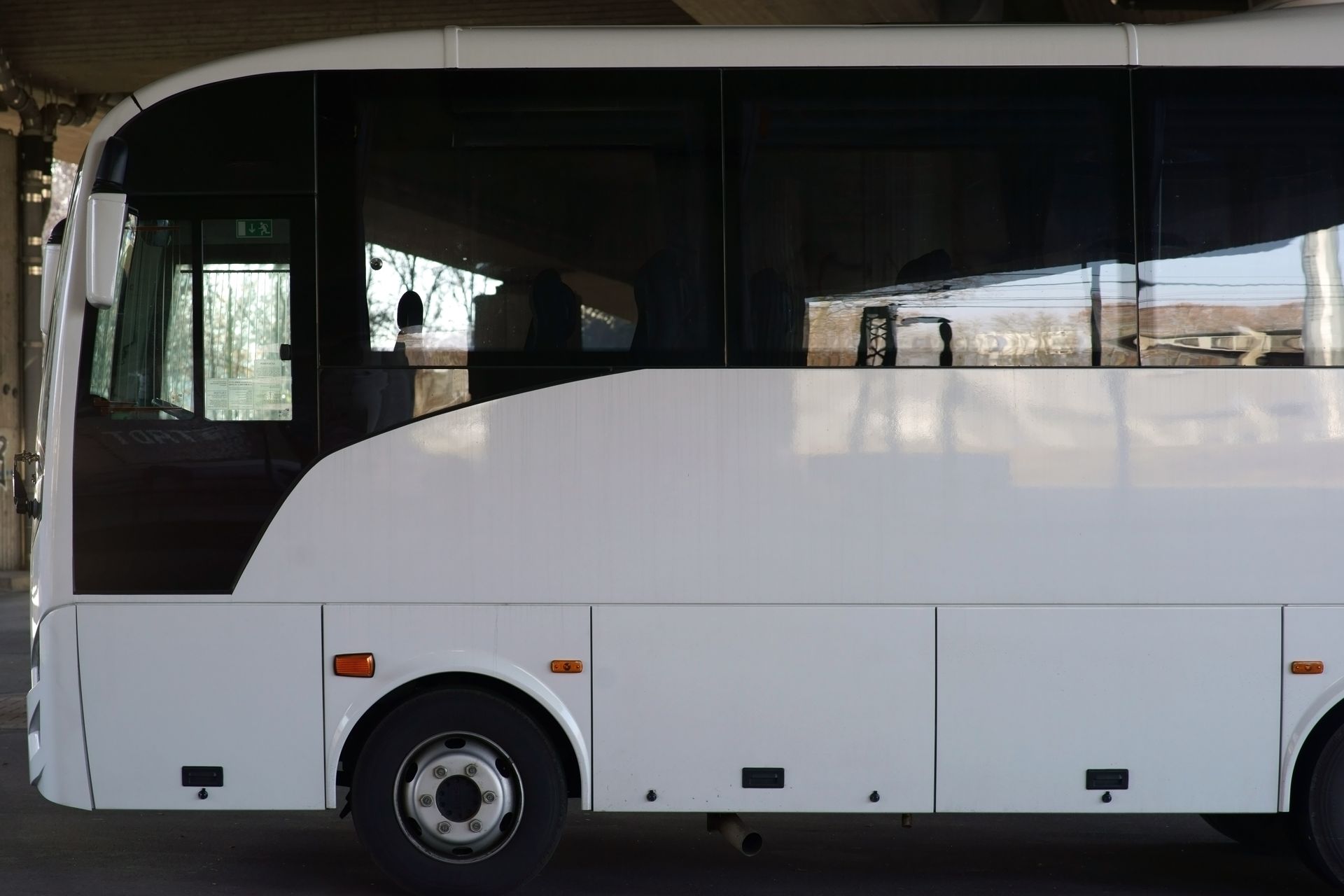 Vue latérale d'un bus blanc stationné sous un bâtiment.