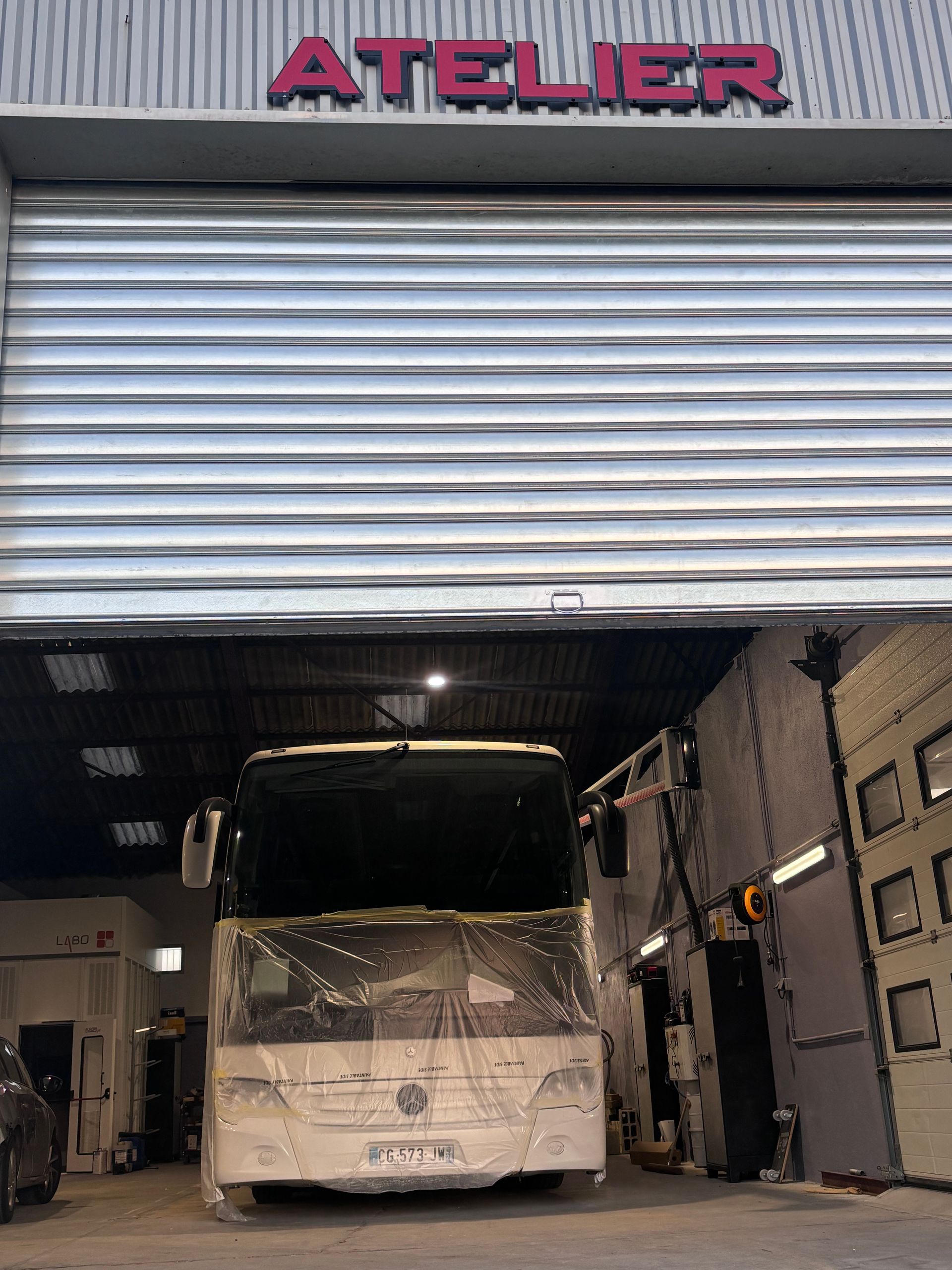 Un bus touristique blanc roule sur une autoroute bordée d'arbres, au coucher du soleil, sous un soleil radieux.