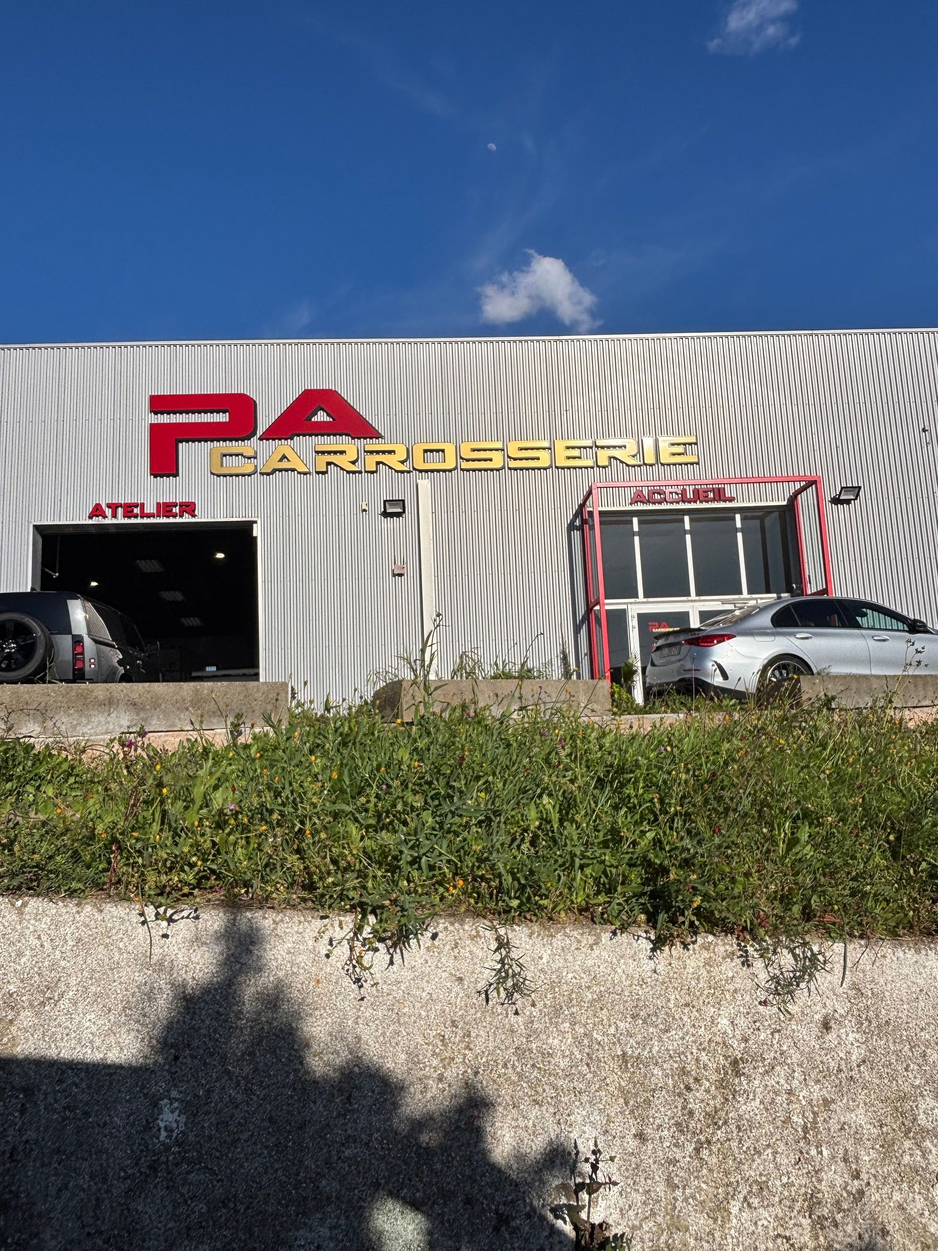 Une voiture argentée avec un pare-chocs arrière froissé et un feu arrière allumé, vue de côté.