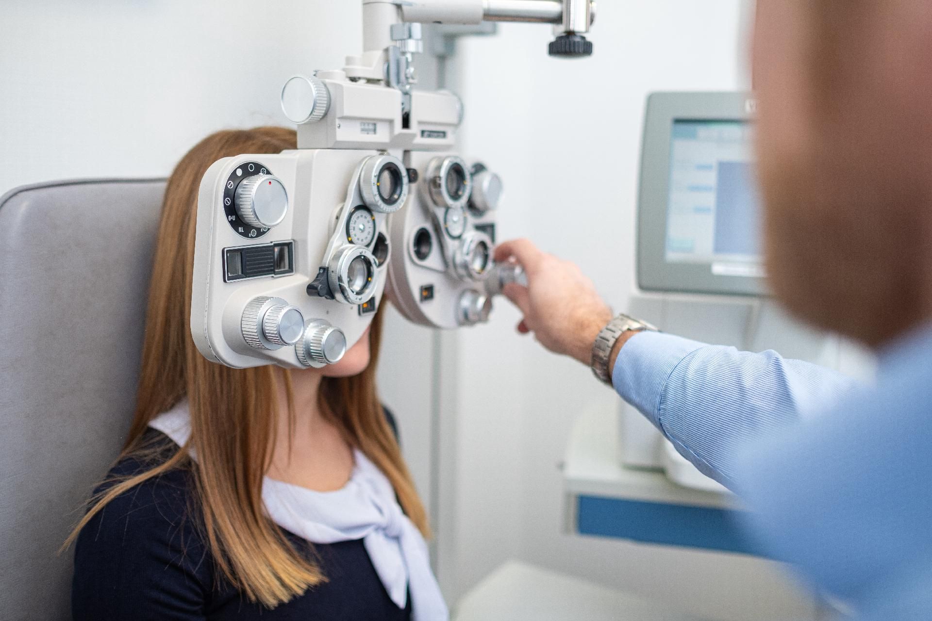 Eine Frau unterzieht sich einer Augenuntersuchung; der Optiker justiert den Phoropter