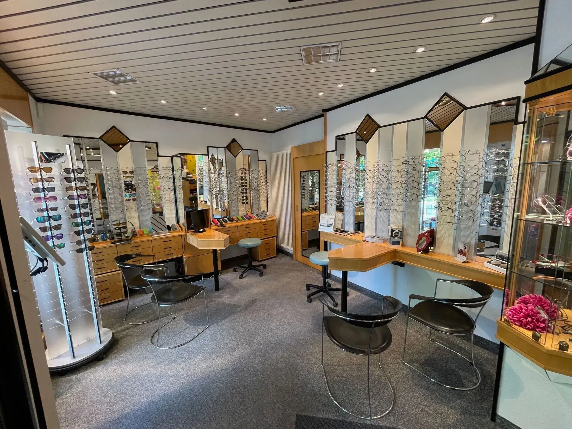 Innenansicht eines Optikergeschäfts mit Brillenauslagen, Spiegeln und Sitzgelegenheiten