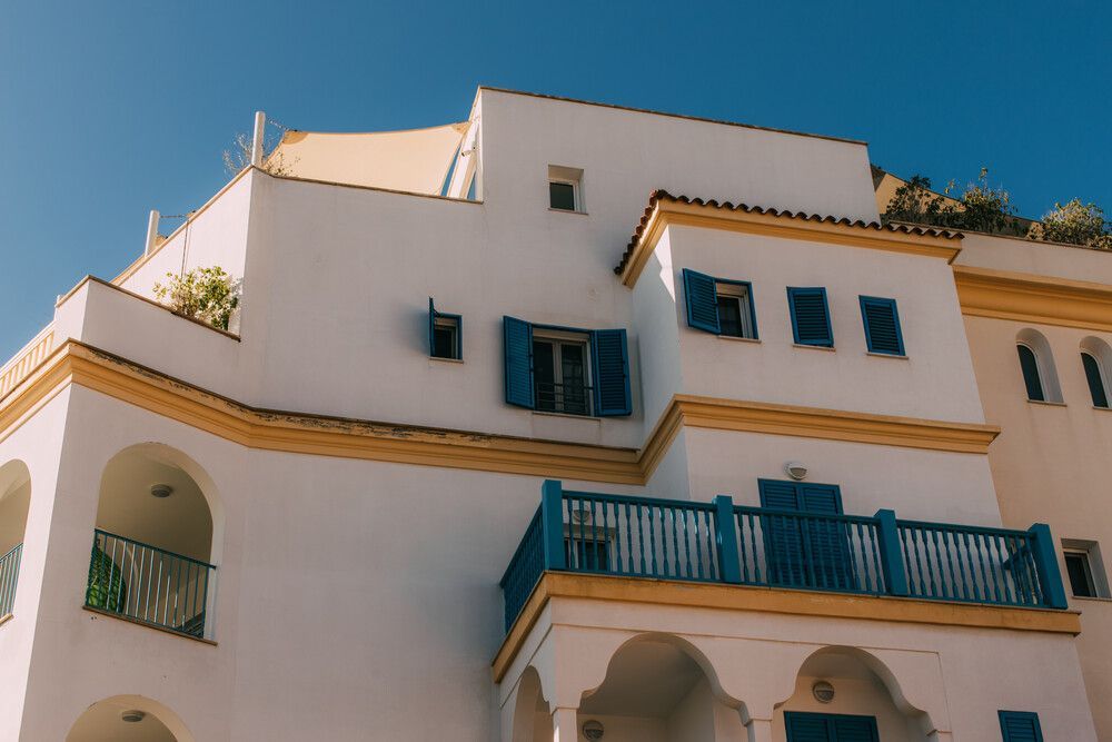 Un gran edificio blanco con contraventanas azules en las ventanas.