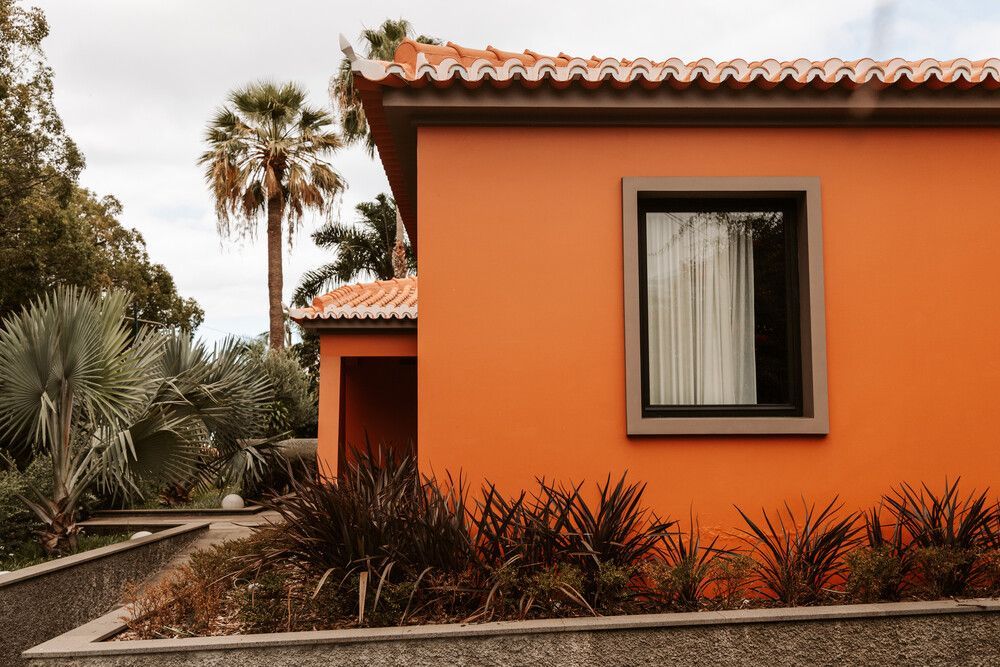 Una casa naranja con una ventana y una palmera al fondo.