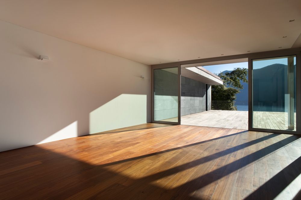 Una habitación vacía con pisos de madera y puertas corredizas de vidrio.