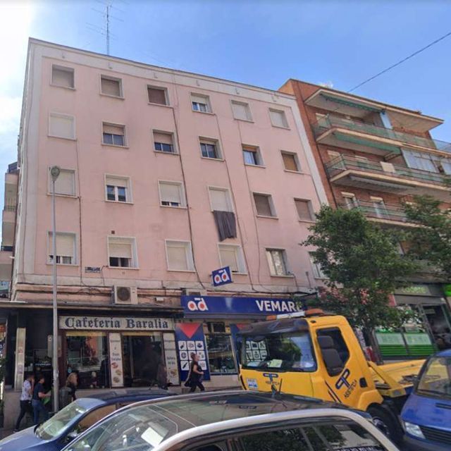 Un camión vemar amarillo está estacionado frente a un edificio