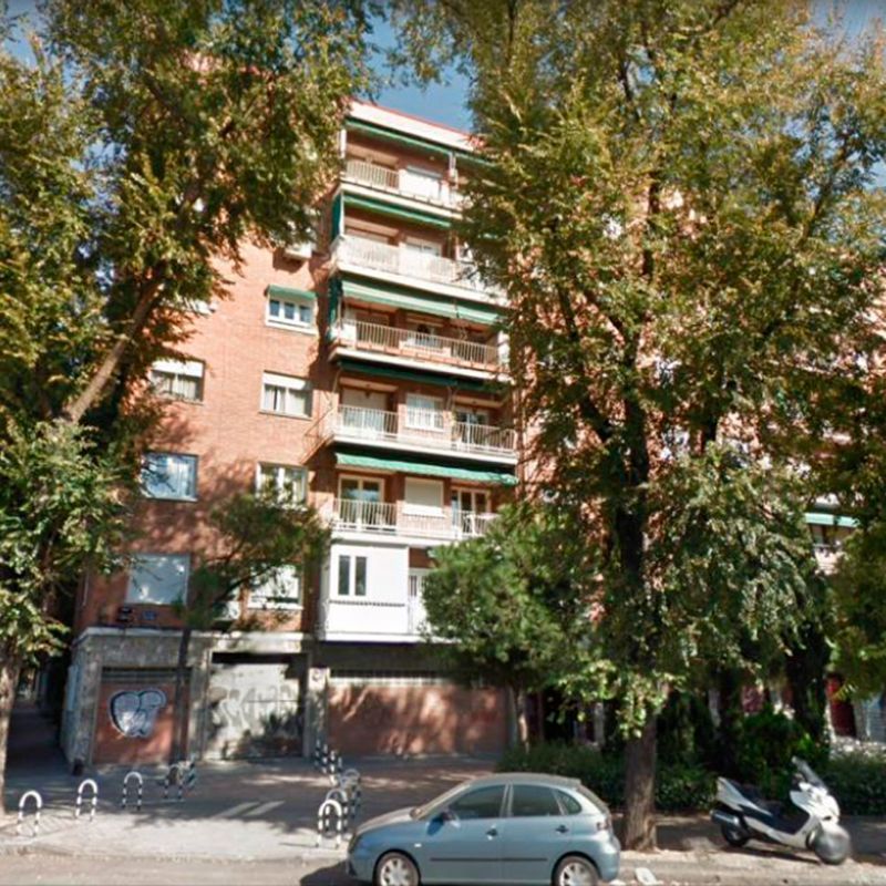 Un coche azul está aparcado delante de un edificio de ladrillo.