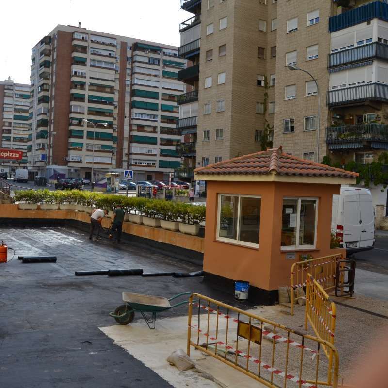 Un pequeño edificio en medio de una ciudad con una carretilla delante de él.