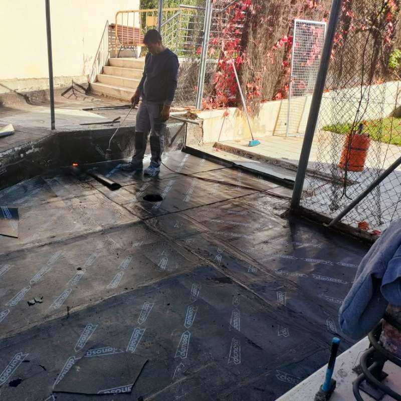 Un hombre está parado sobre un piso de concreto con una cerca de alambre al fondo.