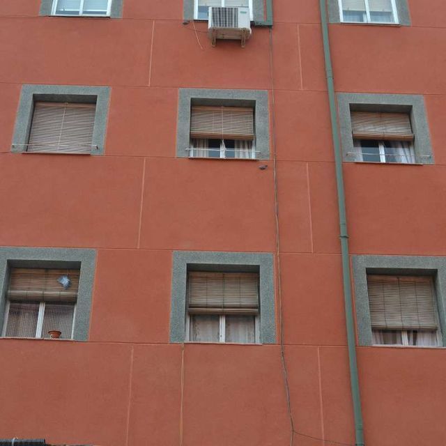 Un edificio con muchas ventanas y un ventilador en el lateral.