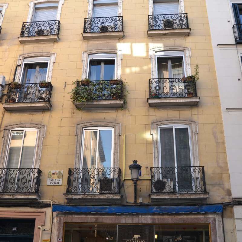 Un edificio amarillo con balcones y un cartel que dice 