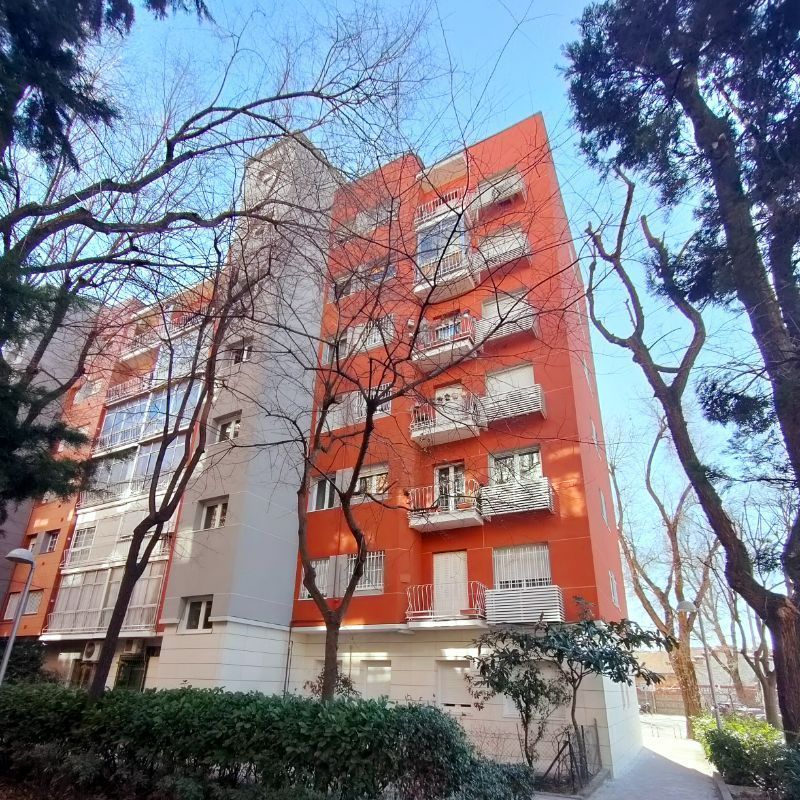 Un edificio de apartamentos naranja y blanco con árboles en el frente.