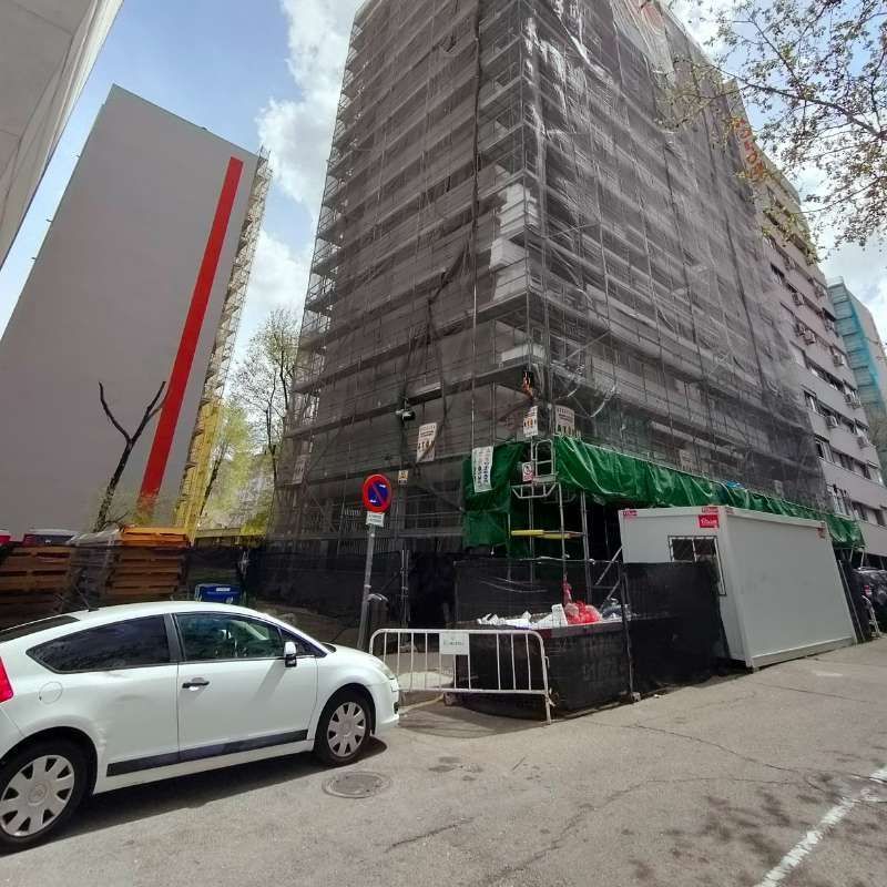Un coche blanco está aparcado delante de un edificio en construcción.