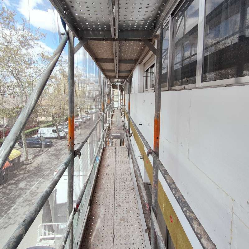 Una pasarela larga con andamios al costado de un edificio.