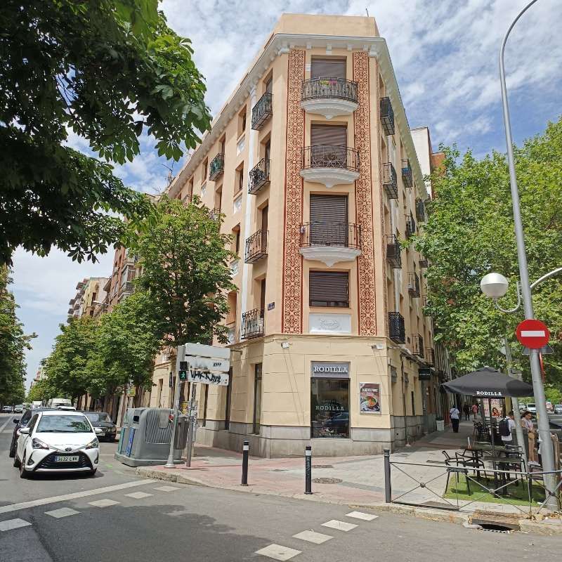 Un coche blanco está aparcado delante de un gran edificio.