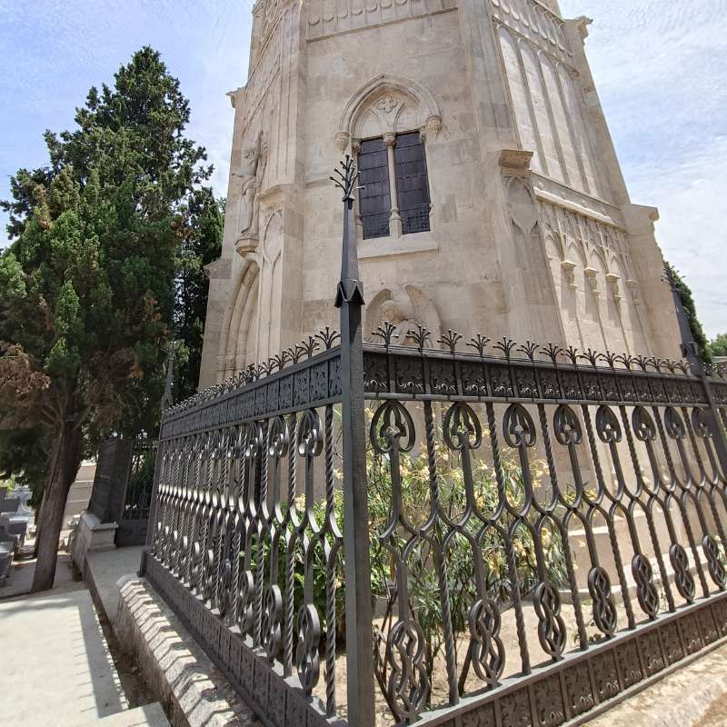 Una valla de hierro forjado rodea un edificio muy alto