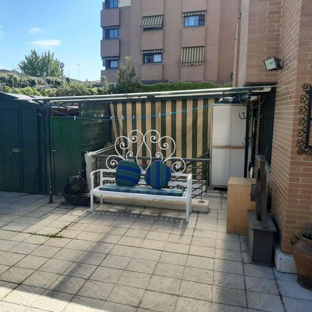 Un banco blanco con cojines azules se encuentra en un patio frente a un edificio.