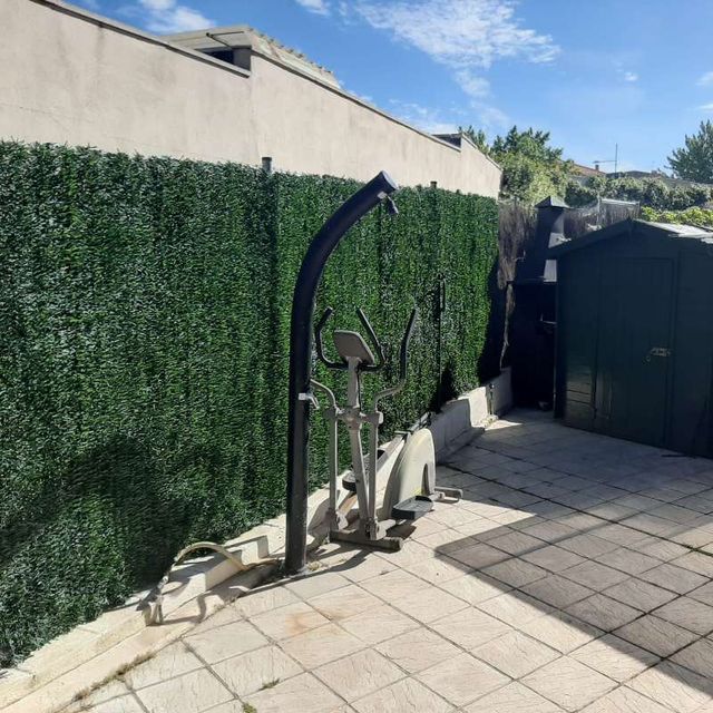 Una bicicleta está estacionada frente a una valla verde