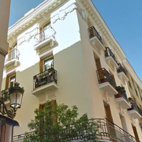 Un edificio blanco con balcones y una lámpara en el lateral.
