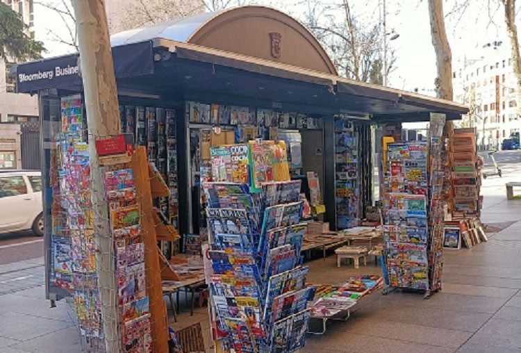 Un quiosco lleno de revistas y libros en una acera.