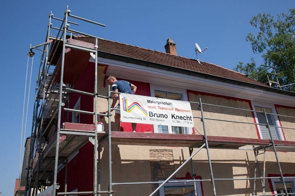 Maler auf einem Gerüst vor einem Haus