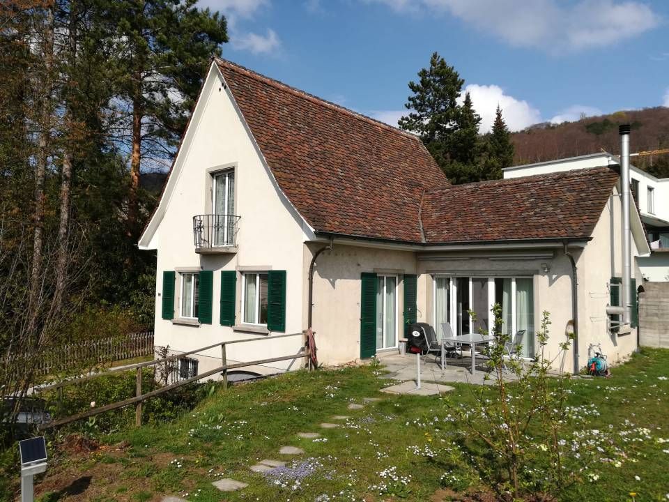 Haus mit heller Fassade und grünen Fensterbrettern