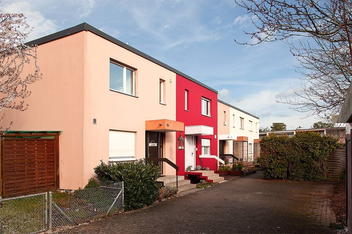 Reihenhäuser mit neuem Anstrich. Das mittlere Haus hat eine rote Fassade.