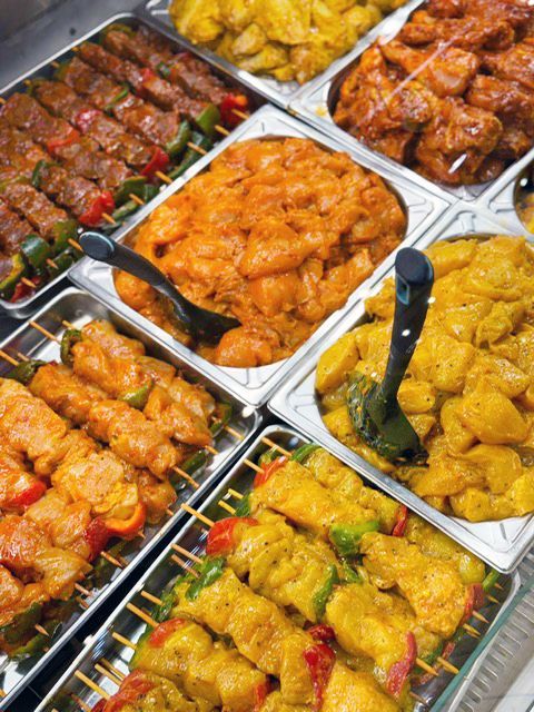 Vitrine avec diverses brochettes de viande marinées et plats de poulet préparés.