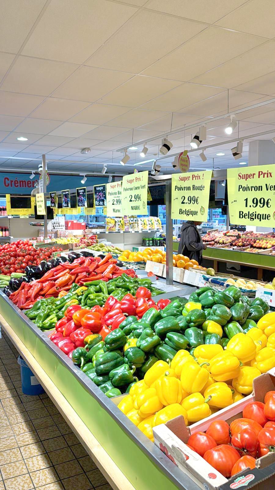 Présentation d'un rayon fruits et légumes. Différents étalages de poivrons verts, rouges et jaunes. Étalage de tomates, aubergines.