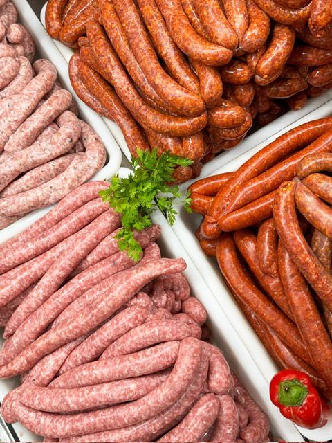 Assortiment de saucisses de différentes couleurs : rose clair, brun rougeâtre et brun foncé, présentées dans des plateaux blancs.