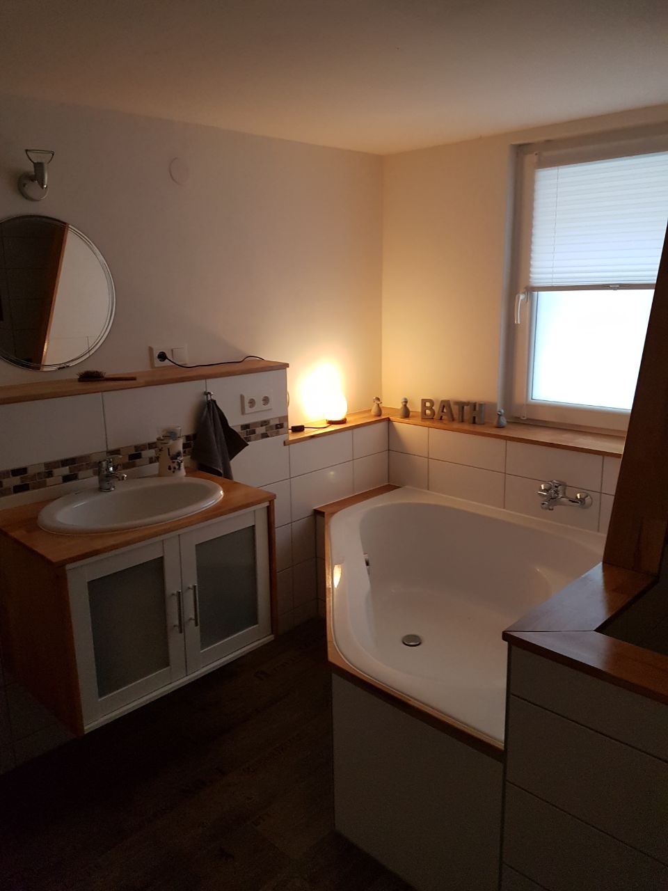 Ein Badezimmer mit Badewanne, Waschbecken, Spiegel und Fenster.