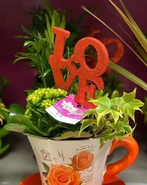 Una taza de té con flores y un símbolo de amor en la parte superior.