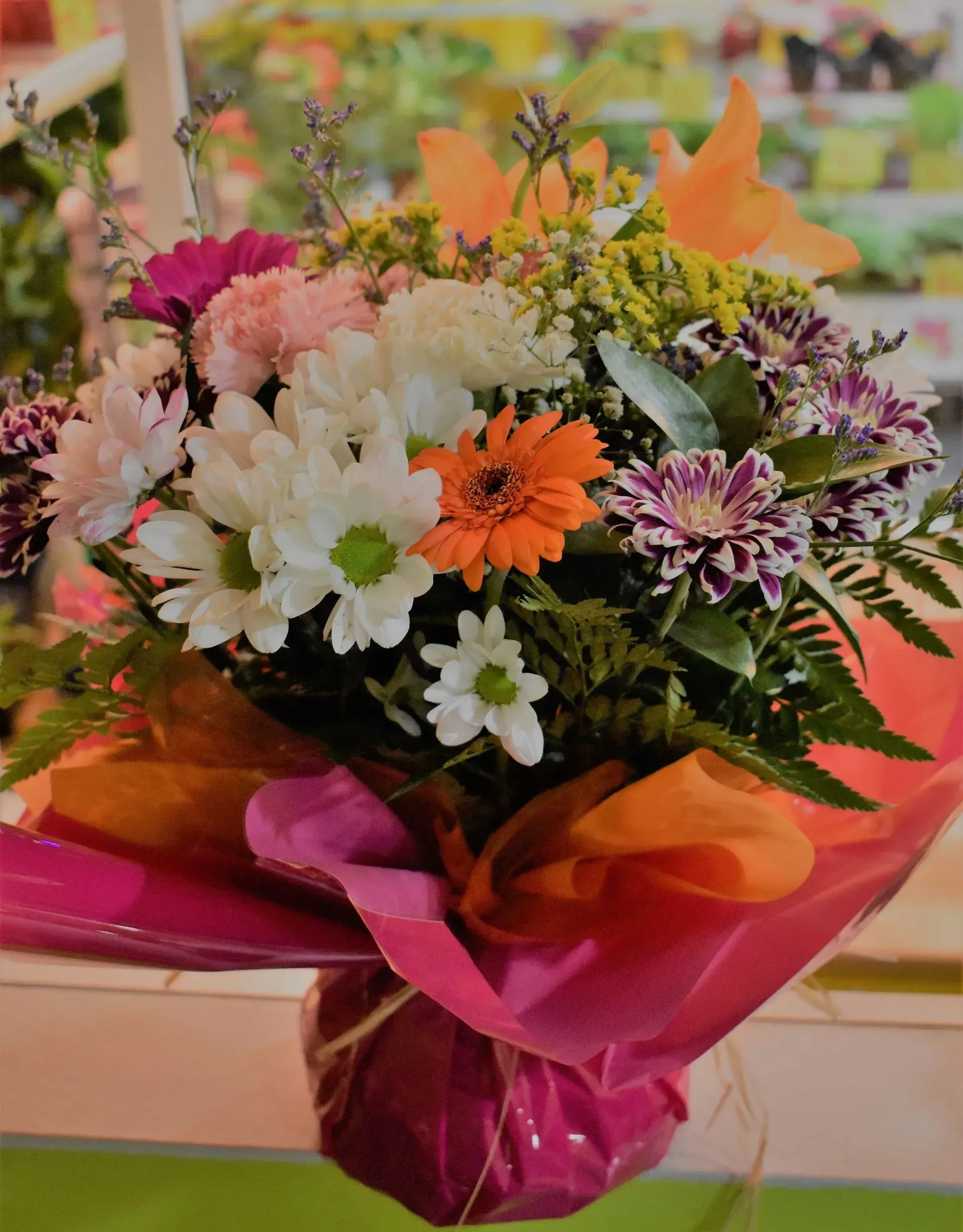 Un ramo de flores envuelto en papel rosa y naranja.