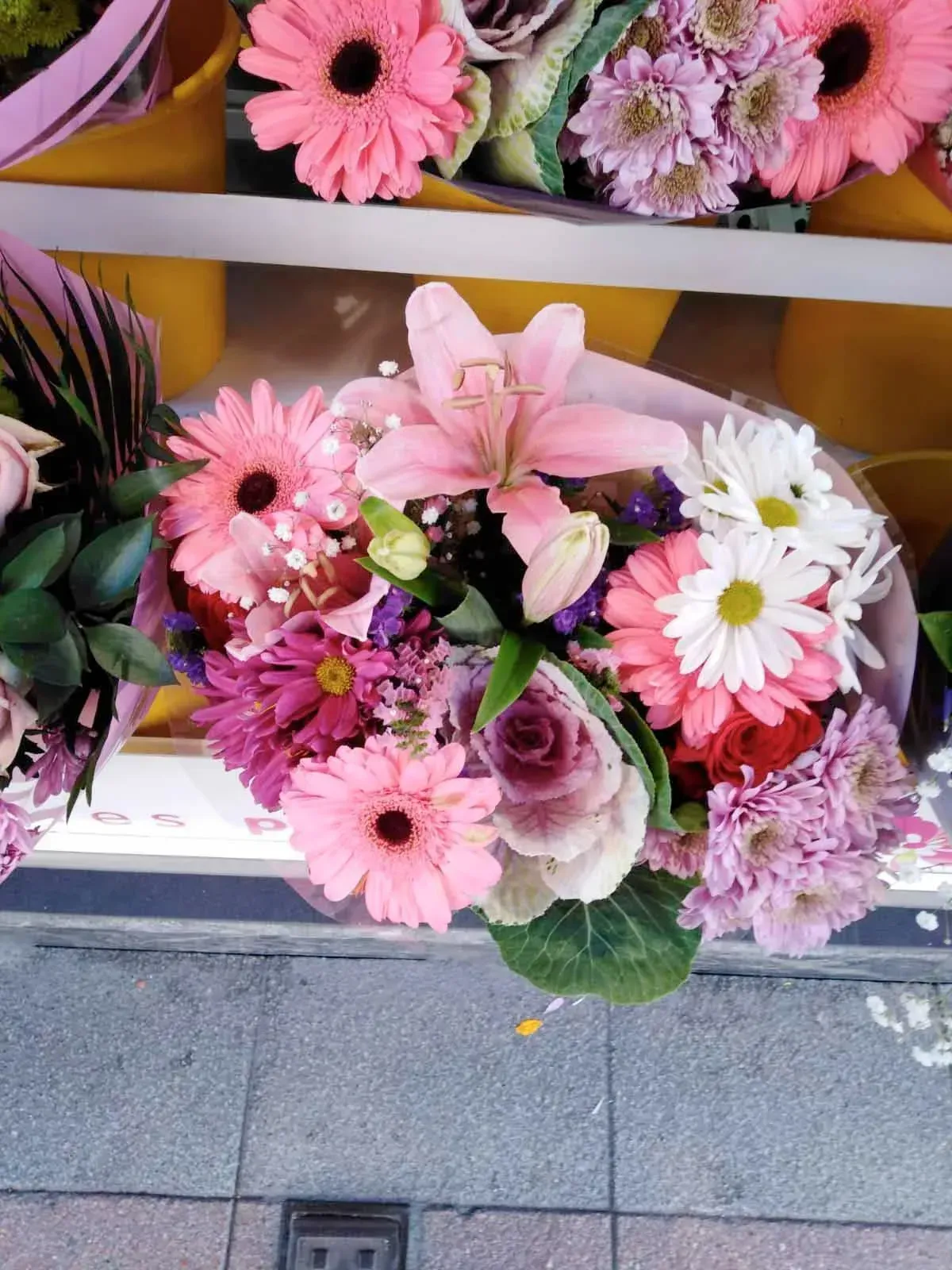Un ramo de flores rosas y moradas en una acera.