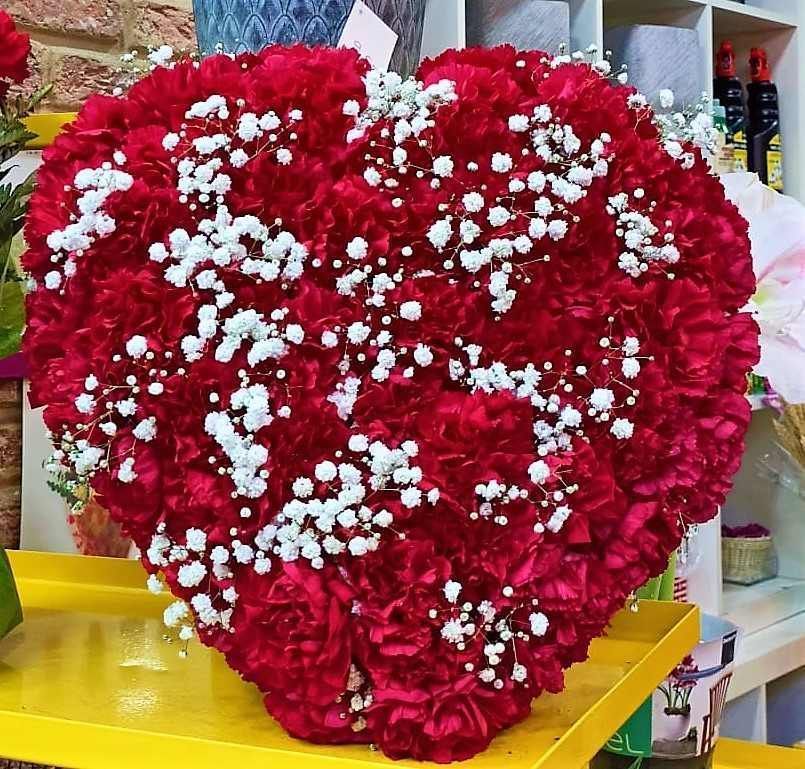 Un ramo en forma de corazón de claveles rojos y gitanos.