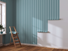Un papier peint turquoise à rayures verticales est partiellement posé sur un mur jouxtant un escabeau en bois dans une pièce.
