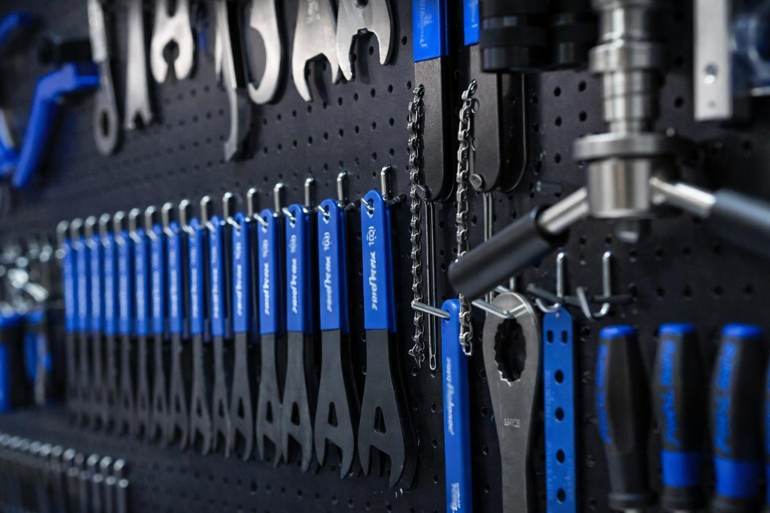 Herramientas de bicicleta de color azul y negro organizadas en un tablero perforado.