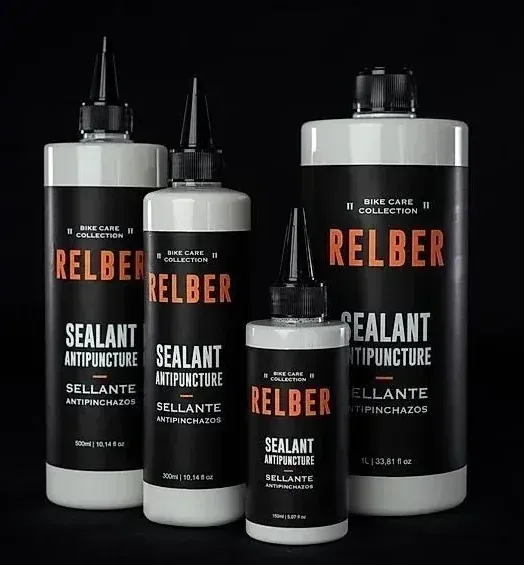 Cuatro botellas de sellador de neumáticos RELBER sobre un fondo negro.