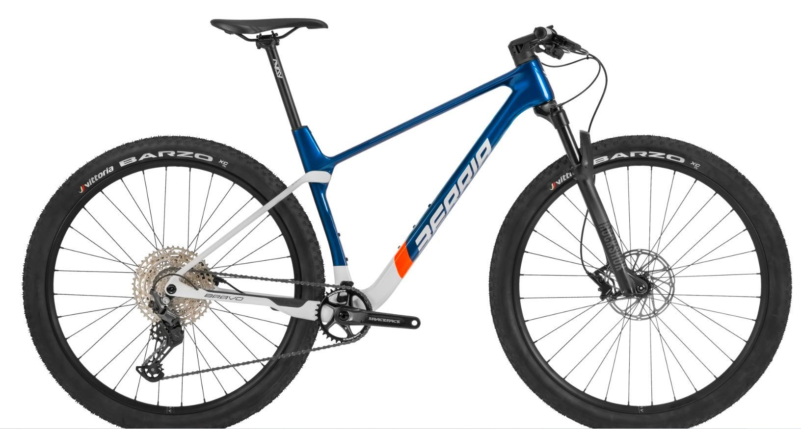 Bicicleta de montaña verde con neumáticos y componentes negros, expuesta en el interior.