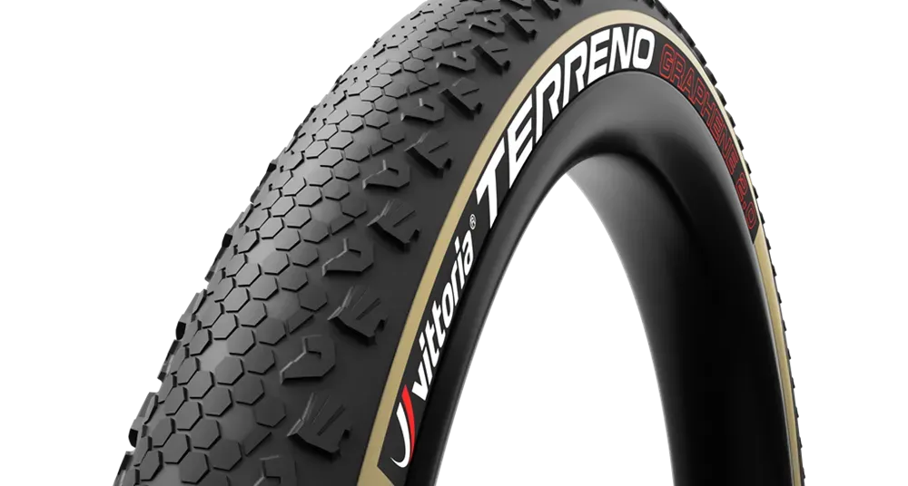Neumático de bicicleta de grava de color negro y tostado con texto Terreno en la llanta.