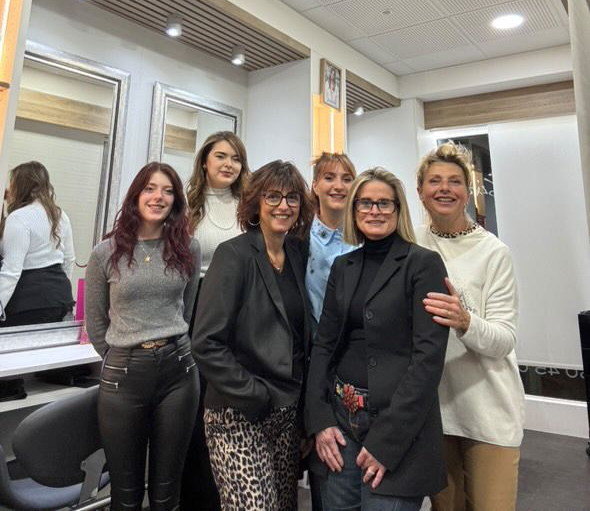 Groupe de femmes souriantes, debout dans un salon avec des miroirs.