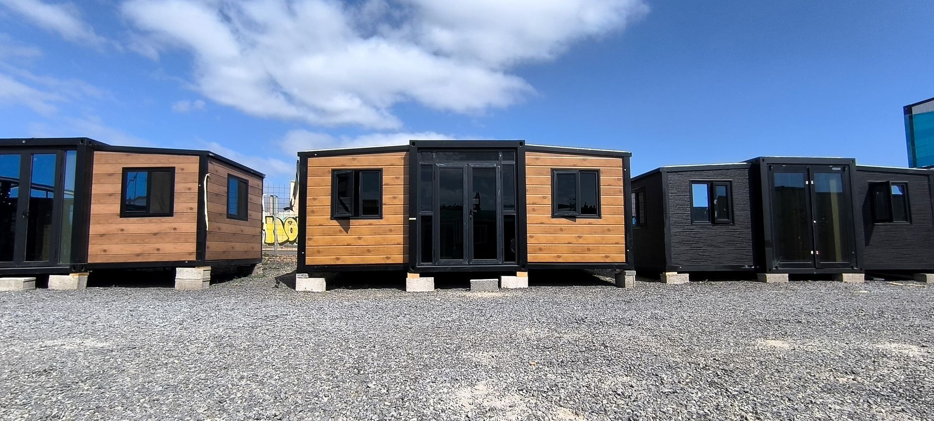 Pequeñas cabañas de madera alineadas sobre grava bajo un cielo azul